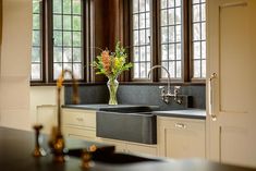 a vase with flowers in it sitting on the counter next to a sink and windows