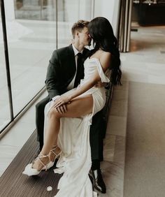 a man and woman sitting next to each other on a bench in front of a window