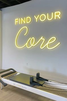 a neon sign that says find your core on the wall above a treadmill in a gym