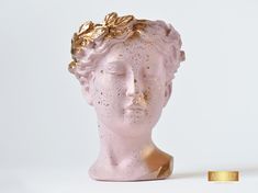 a pink statue with gold leaves on it's head