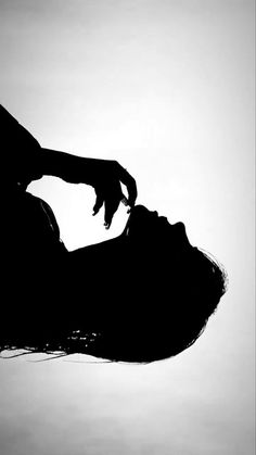 the silhouette of a woman's head with her hand over her face