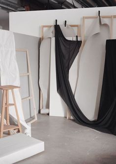 an art studio with white walls and black drapes hanging on the wall next to wooden ladders