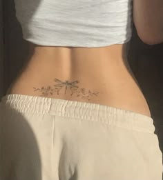 the back of a woman's stomach with a small dragonfly tattoo on it