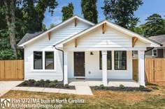 a small white house sitting in the middle of a yard next to a wooden fence