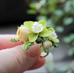 a hand holding a tiny ring with flowers on it