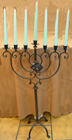 a menorah with seven lit candles on it's stand, in front of a tan table cloth