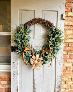 a wreath with deer antlers is hanging on the front door