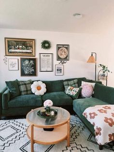 a living room with green couches and pictures on the wall above it, along with a coffee table