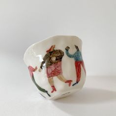 a small white bowl with people painted on it