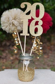 a mason jar filled with gold glitter and two white flowers on top of a table