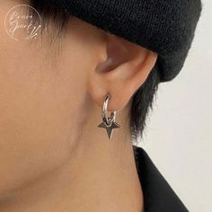 a close up of a person wearing a black hat and silver earring with an arrow on it