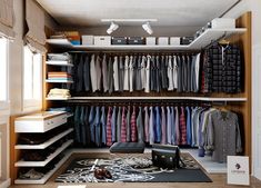 an organized closet with clothes and shoes on the floor, including shirts hanging from shelves