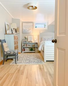 an open door leading to a bedroom with white walls and wood floors, along with a chair