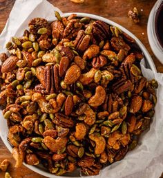 a white bowl filled with nuts on top of a wooden table