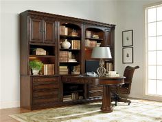 an office desk with bookshelf and chair in front of the window, next to a rug