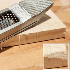 a grater sitting on top of a wooden table next to a piece of wood