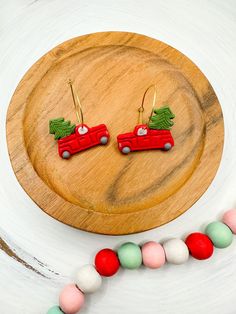 a pair of christmas themed earrings on a wooden platter next to candy balls and beads