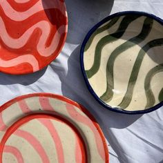 three plates with different designs on them sitting on a white tablecloth covered table cloth