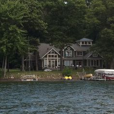 a boat is parked in front of a large house on the water's edge