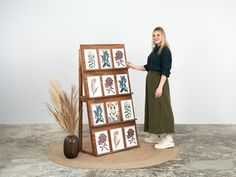 a woman standing next to a wooden display case with pictures on it and flowers in the middle