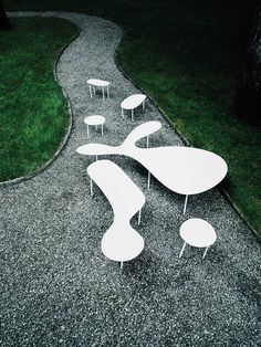 several tables and stools are arranged on the gravel path