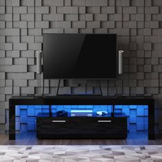 an entertainment center with a television on top and blue lights in front of the tv