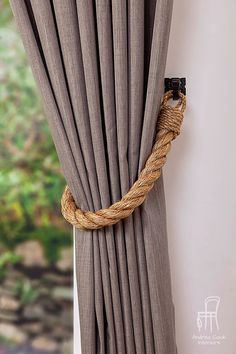 a rope hanging on the side of a window next to a curtain with curtains pulled back