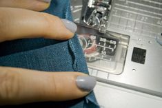 a woman's hands with grey nail polish on her nails working on a sewing machine