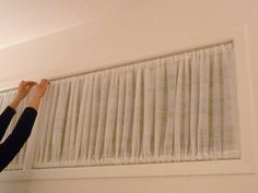 a woman is working on an air conditioner in the living room with white curtains