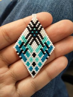 a hand holding a beaded brooch in it's palm