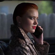 a woman sitting in the back seat of a car talking on a cell phone