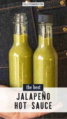 the best jalapeno hot sauce is in two glass bottles, one being held by someone's hand