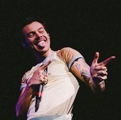 a man with tattoos on his arm giving the peace sign while standing in front of a microphone