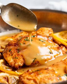 a spoon drizzling gravy over some chicken in a skillet