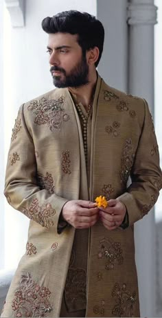 a man with a beard wearing a brown suit and yellow flower in his lapel