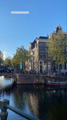 a small boat is on the water in front of some buildings and people riding bikes