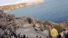 a group of people standing on top of a cliff next to the ocean and cliffs