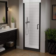 a bathroom with a walk in shower next to a white sink and black vanity mirror