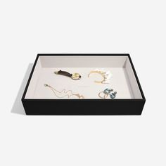 an open box with various jewelry items in it on a white surface, top view