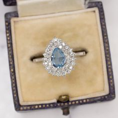 an engagement ring with a blue topaz surrounded by white and clear diamonds in a box