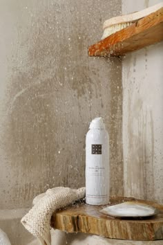 a white spray bottle sitting on top of a wooden table next to a towel and pillow