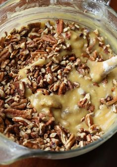 a glass bowl filled with oatmeal and pecans on top of a wooden table