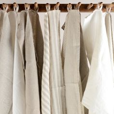 several towels hanging on a wooden rail in front of a white wall and wood frame