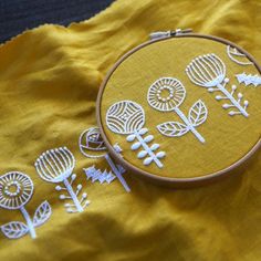 an embroidery project with flowers and leaves on a yellow fabric background is featured in this close up photo