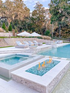 an outdoor swimming pool with lounge chairs and umbrellas in the background, surrounded by trees