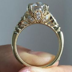 a close up of a person's hand holding an engagement ring