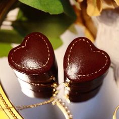 two heart shaped wooden boxes sitting on top of a table next to a gold chain