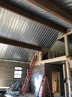 the inside of a house being built with metal sheets on the ceiling and ladders