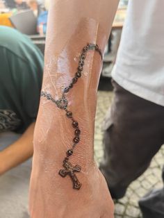 a person with a rosary tattoo on their arm