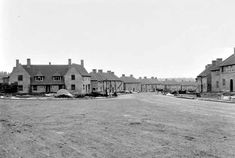 an old black and white photo of some houses in the middle of a dirt road